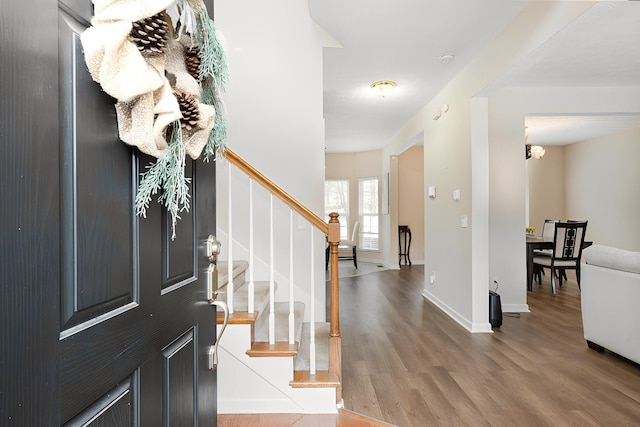 foyer entrance with stairs, wood finished floors, and baseboards