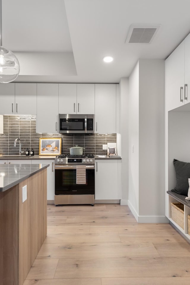 kitchen featuring visible vents, decorative backsplash, light wood-style flooring, appliances with stainless steel finishes, and modern cabinets