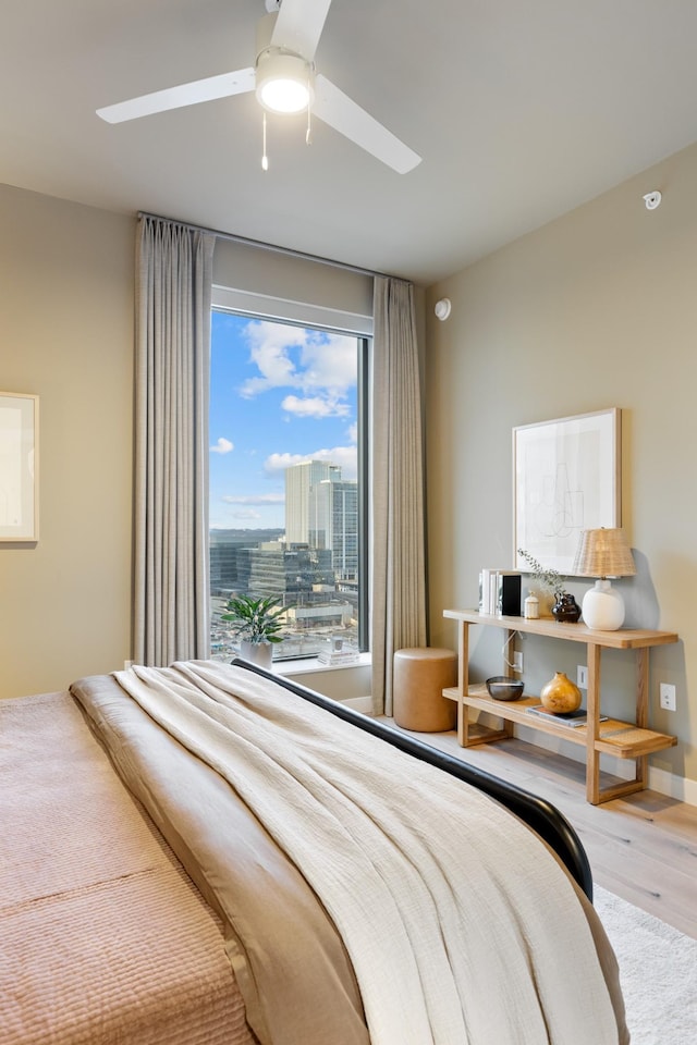 bedroom featuring a city view, a ceiling fan, and wood finished floors