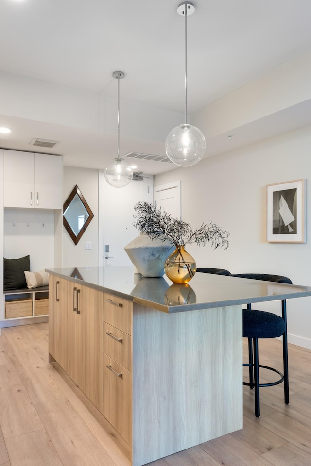 kitchen with visible vents, light wood-style flooring, light brown cabinetry, modern cabinets, and a center island