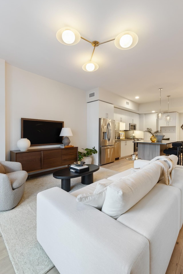 living room featuring recessed lighting, visible vents, and light wood-type flooring