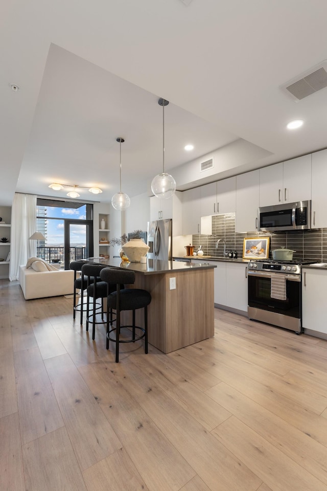 kitchen with visible vents, stainless steel appliances, light wood-style floors, dark countertops, and modern cabinets