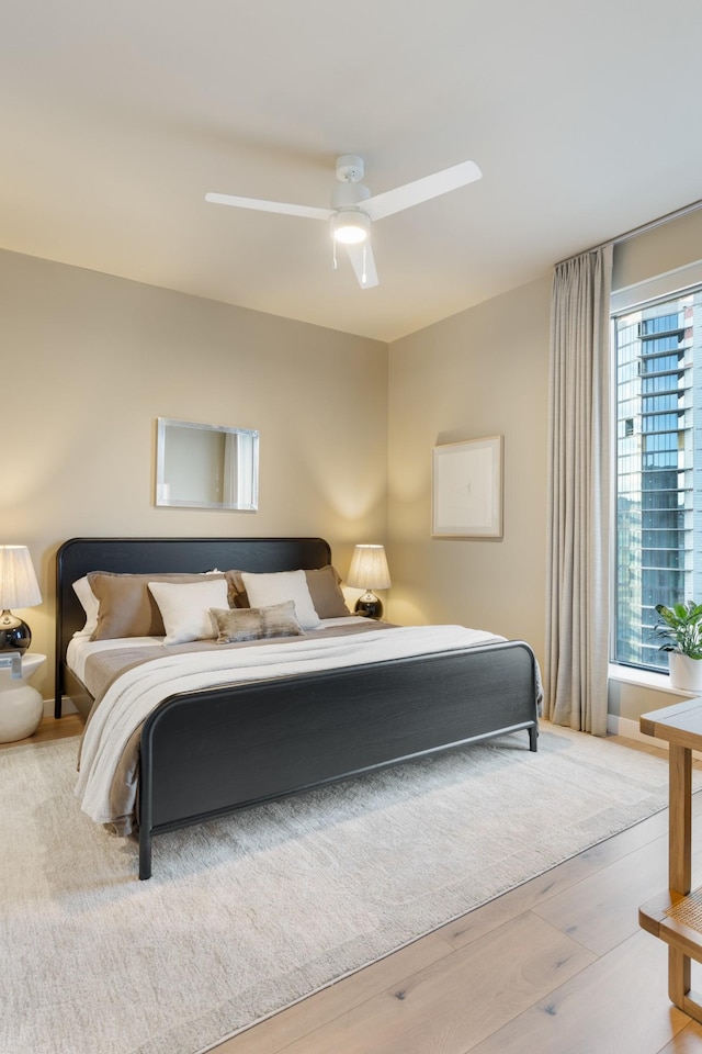 bedroom with a ceiling fan, wood finished floors, and baseboards