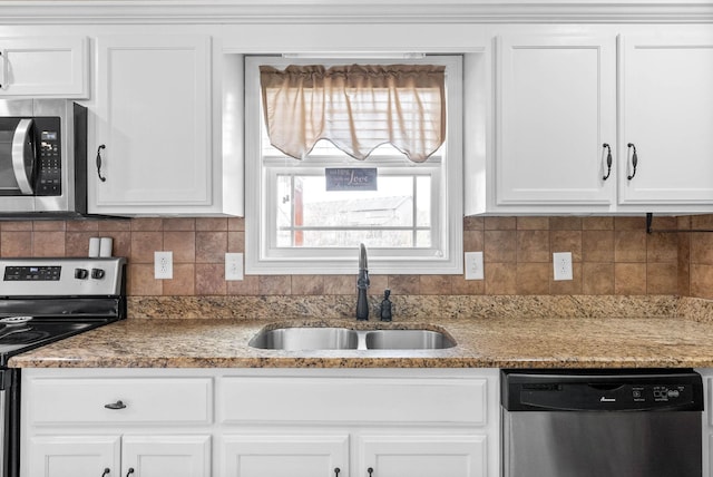 kitchen with stainless steel appliances, decorative backsplash, a sink, and white cabinets