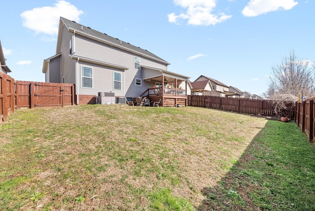 back of property with a lawn, a fenced backyard, a gate, a deck, and central air condition unit