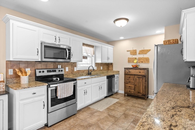 kitchen featuring appliances with stainless steel finishes, white cabinets, a sink, and tasteful backsplash