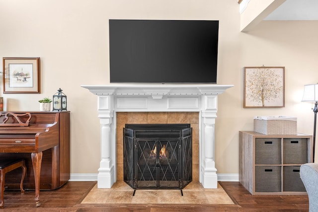 interior details featuring a tiled fireplace, baseboards, and wood finished floors