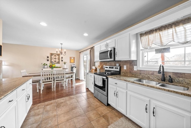 kitchen with white cabinetry, decorative backsplash, stainless steel appliances, and a sink