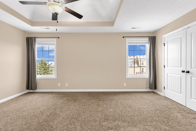 unfurnished room featuring baseboards, visible vents, a raised ceiling, and carpet flooring