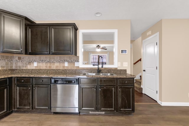 kitchen with tasteful backsplash, dark countertops, stainless steel dishwasher, a sink, and wood finished floors