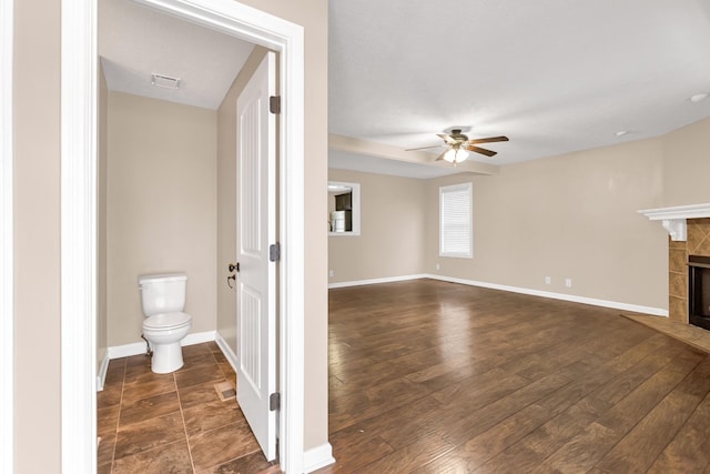 interior space with baseboards, a fireplace, hardwood / wood-style floors, and toilet