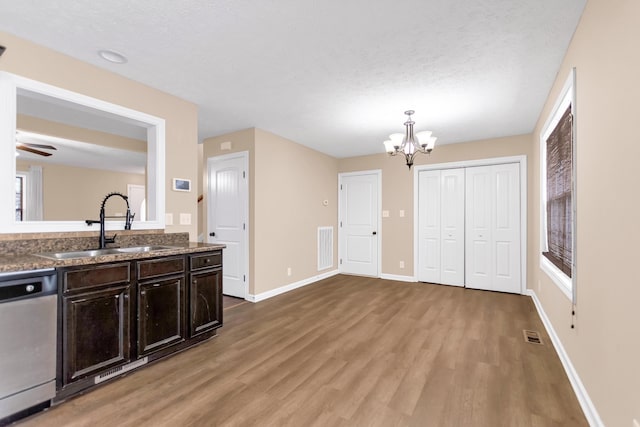 kitchen featuring light wood finished floors, baseboards, visible vents, stainless steel dishwasher, and a sink