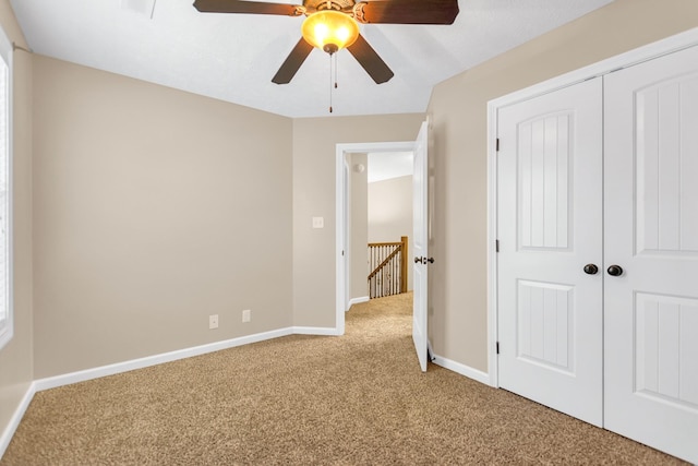 unfurnished bedroom featuring carpet floors, ceiling fan, baseboards, and a closet