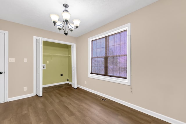 unfurnished dining area with a notable chandelier, wood finished floors, visible vents, and baseboards