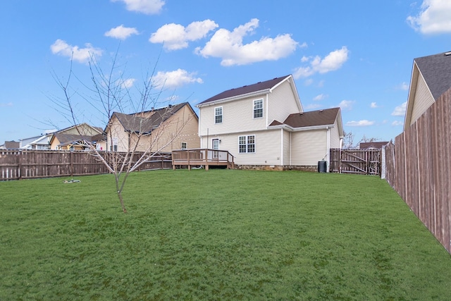 rear view of property with a fenced backyard, a gate, a deck, and a yard