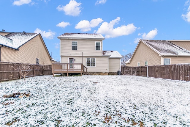 snow covered property with a fenced backyard and a deck