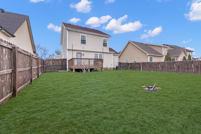 rear view of house with a fenced backyard, a lawn, and a wooden deck