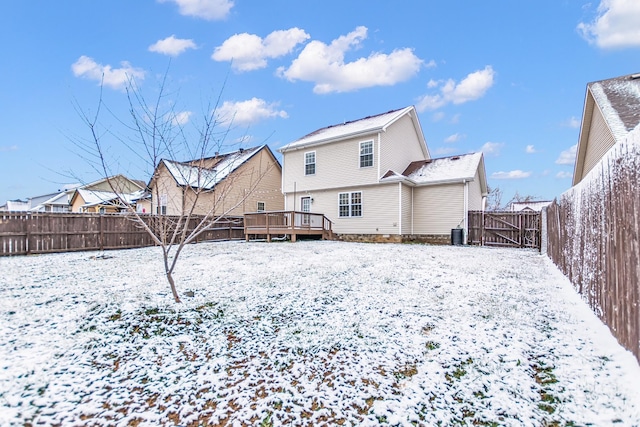 snow covered rear of property featuring a residential view, a gate, a fenced backyard, and a deck