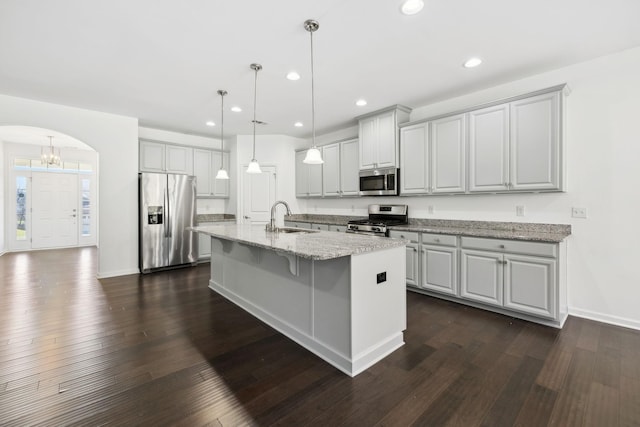 kitchen with appliances with stainless steel finishes, arched walkways, dark wood finished floors, and a sink