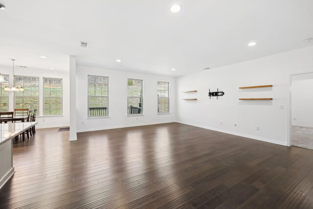 unfurnished living room featuring dark wood-style floors, recessed lighting, baseboards, and an inviting chandelier