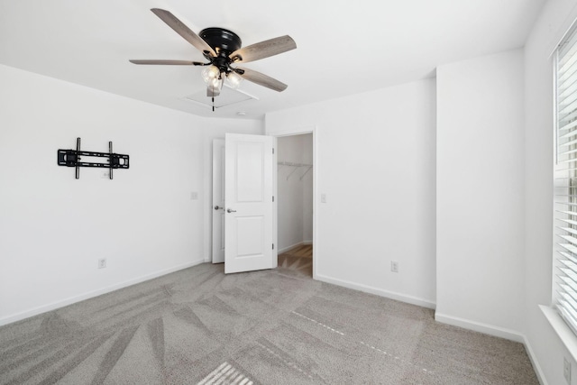 unfurnished bedroom with a ceiling fan, carpet flooring, a spacious closet, and baseboards