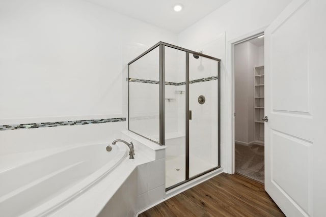 full bathroom featuring a garden tub, a shower stall, a walk in closet, and wood finished floors