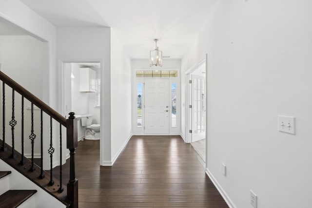 foyer entrance featuring baseboards, stairway, a chandelier, and wood finished floors