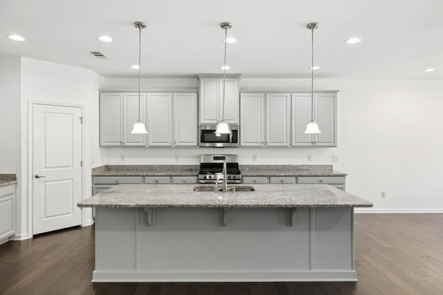 kitchen with visible vents, appliances with stainless steel finishes, dark wood-type flooring, a sink, and light stone countertops