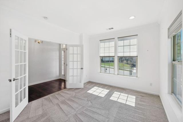 carpeted empty room featuring french doors, a healthy amount of sunlight, crown molding, and visible vents