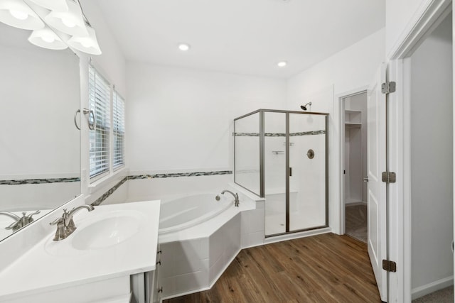 full bathroom with a stall shower, a garden tub, a sink, and wood finished floors