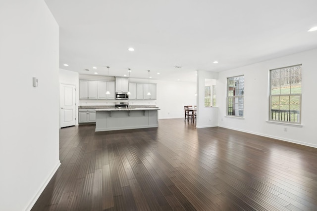 unfurnished living room featuring recessed lighting, dark wood finished floors, and baseboards