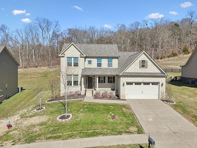 traditional-style house with brick siding, a shingled roof, concrete driveway, and a front yard