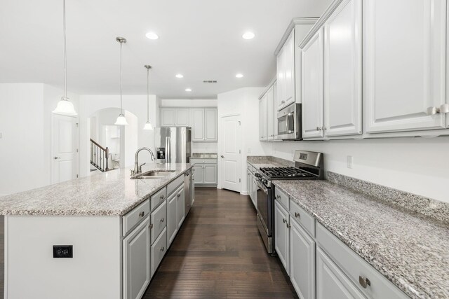 kitchen featuring arched walkways, dark wood-type flooring, a sink, visible vents, and appliances with stainless steel finishes