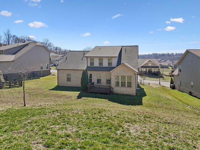 back of property with a residential view, brick siding, and a lawn