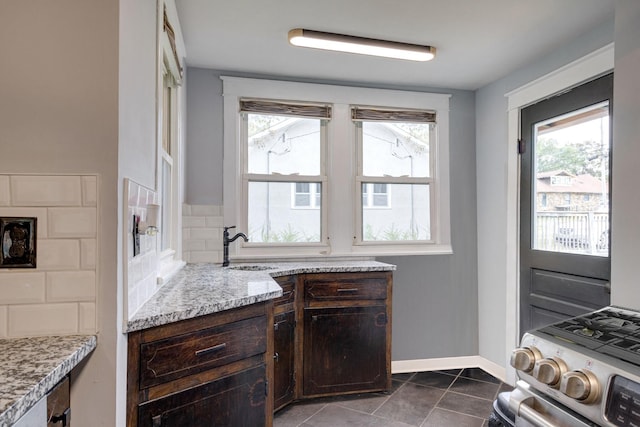 kitchen featuring a sink, plenty of natural light, backsplash, and dark brown cabinetry