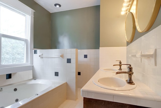 bathroom featuring wainscoting, a sink, tile walls, and a whirlpool tub