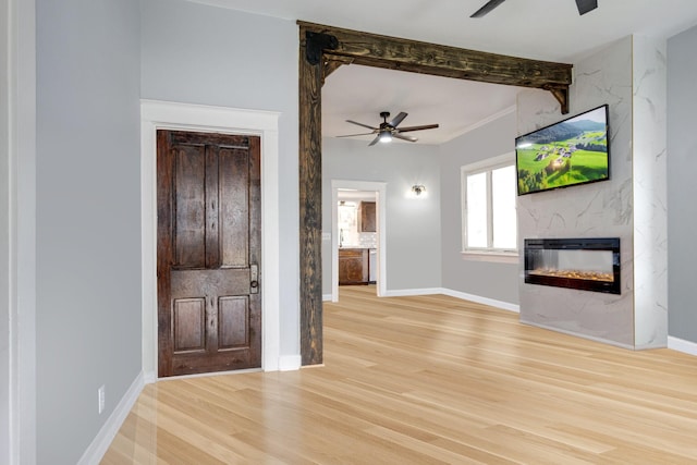 unfurnished living room with ceiling fan, light wood finished floors, beamed ceiling, and a fireplace