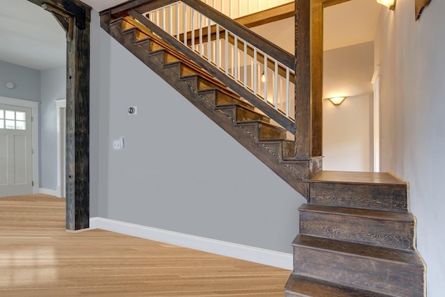 staircase featuring wood finished floors and baseboards