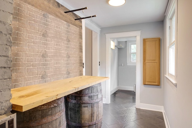 bar with brick wall, baseboards, and stone finish flooring