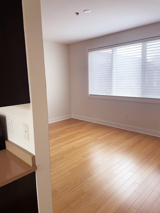 unfurnished room with light wood-style floors and baseboards