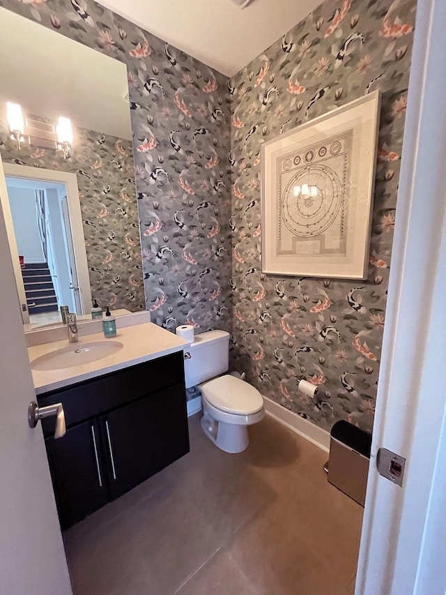 bathroom with wallpapered walls, toilet, vanity, and baseboards