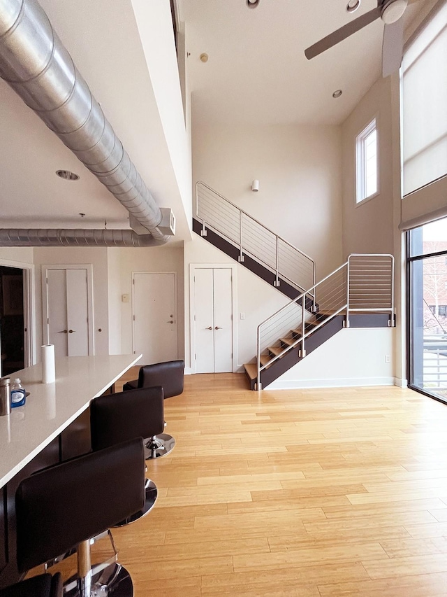 office with light wood-style flooring, a towering ceiling, and ceiling fan