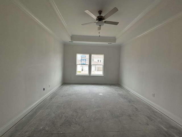 empty room featuring ornamental molding, a raised ceiling, baseboards, and unfinished concrete floors