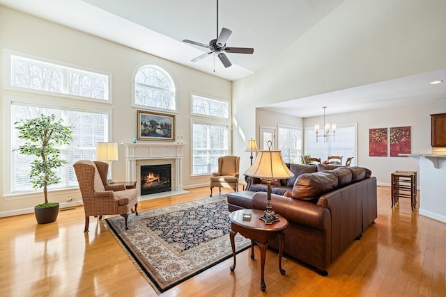 living area with a fireplace with flush hearth, light wood-type flooring, a wealth of natural light, and baseboards