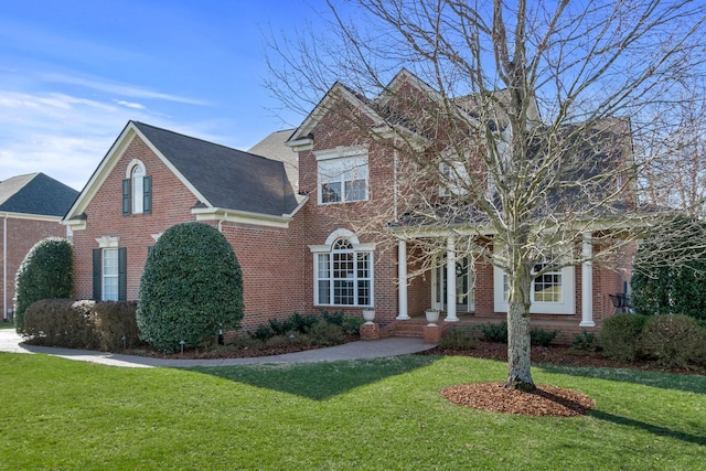 view of front of house featuring brick siding, a front lawn, and roof with shingles