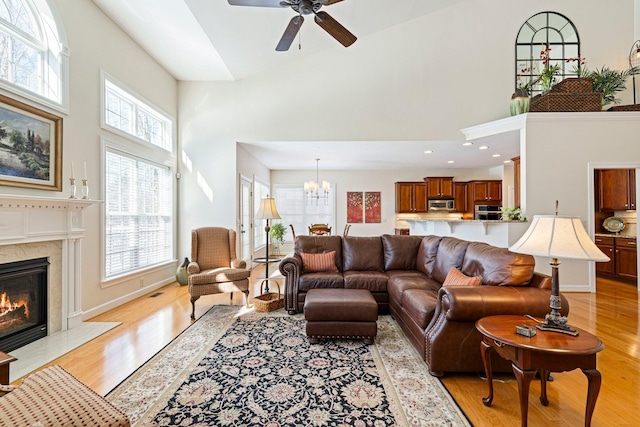 living area with a high end fireplace, a high ceiling, and light wood finished floors