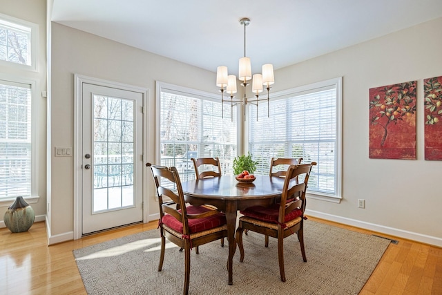 dining space featuring a chandelier, light wood-style flooring, and baseboards