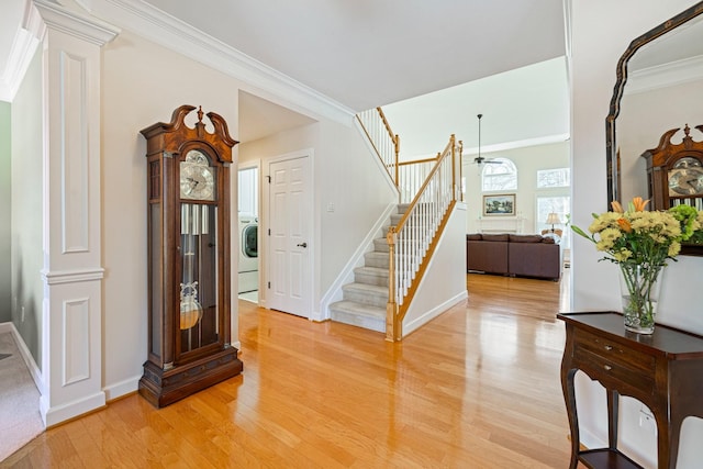 entrance foyer featuring washer / clothes dryer, stairway, light wood finished floors, decorative columns, and crown molding