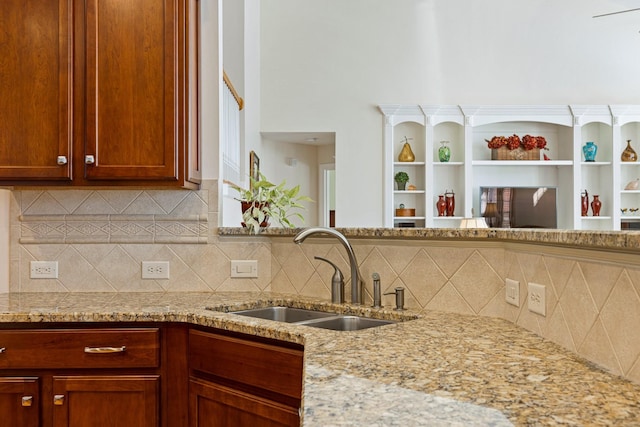 kitchen featuring light stone counters, backsplash, and a sink