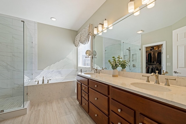 bathroom featuring double vanity, a garden tub, a shower stall, and a sink